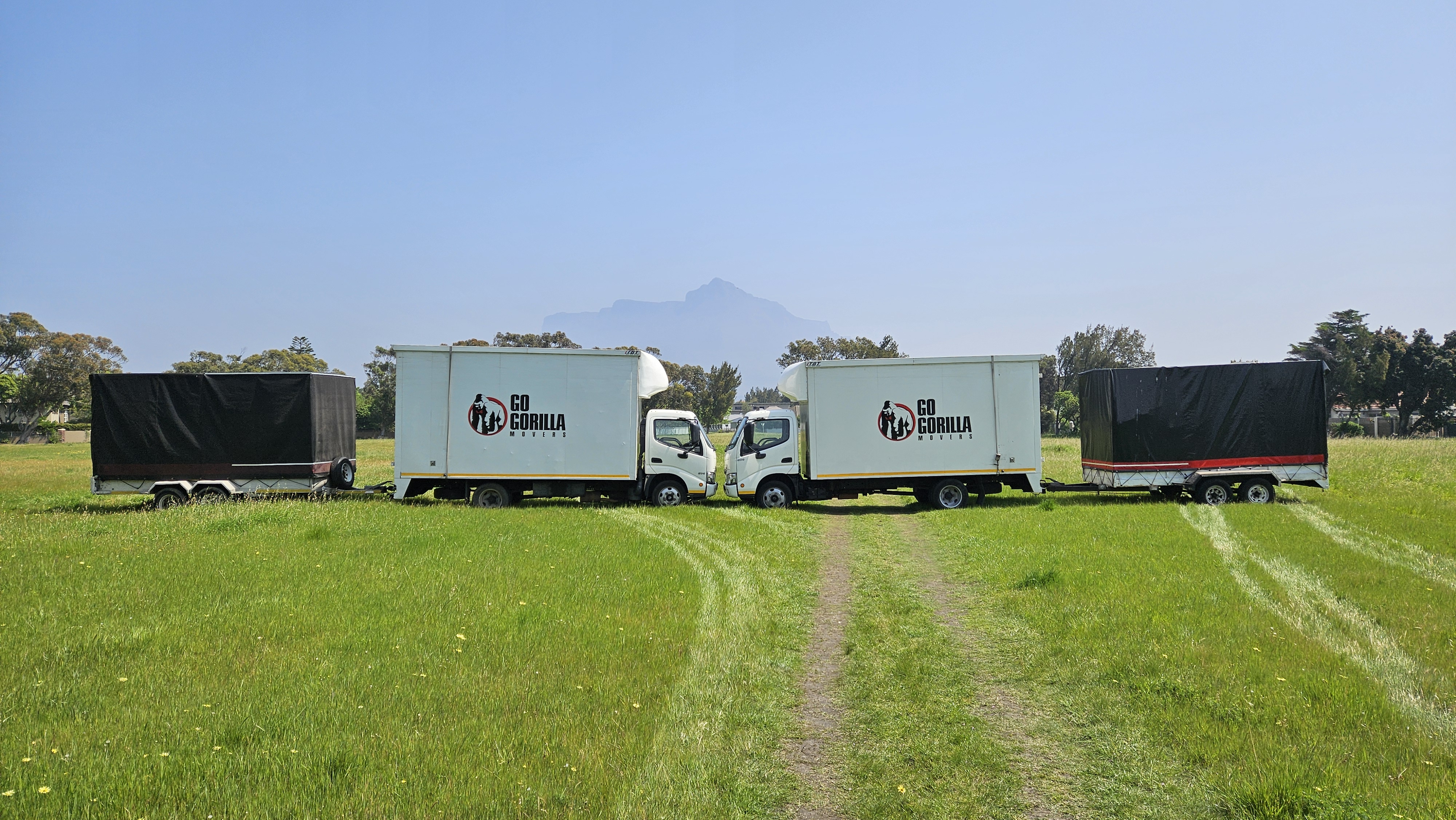 Go Gorilla Movers trucks nose to nose with their custom waterproof trailers and Table Mountain behind